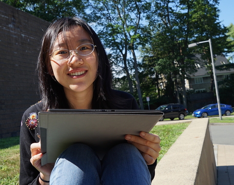 Meng Gu sits outside with a laptop
